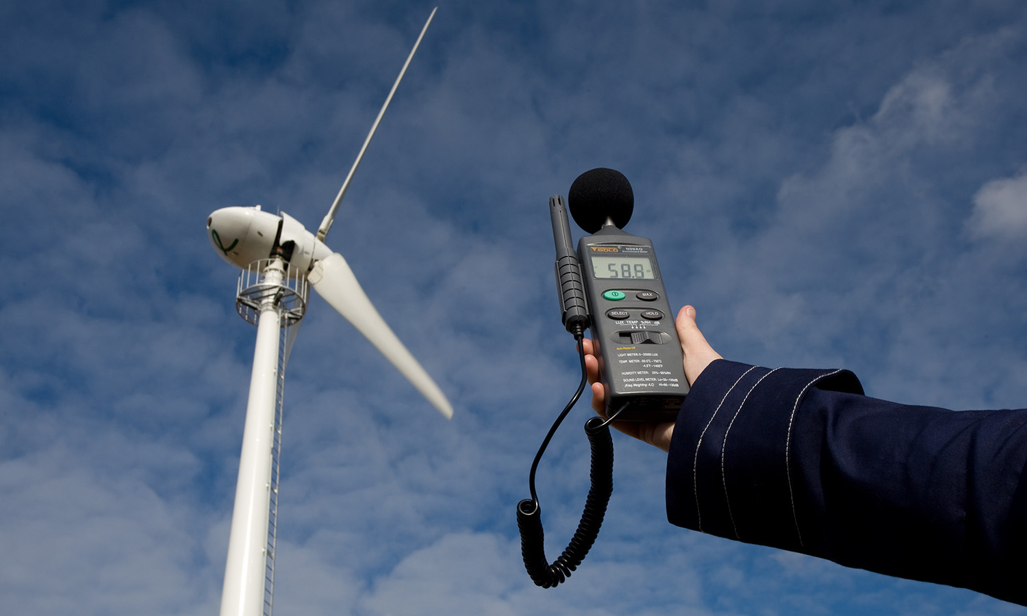 Sound meter pointed at a wind turbine